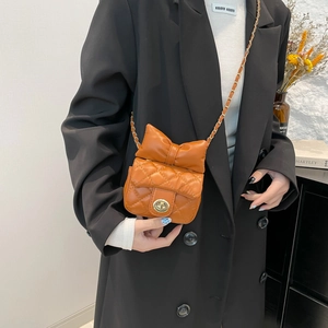 Caramel quilted mini crossbody bag with a large bow detail and gold chain strap