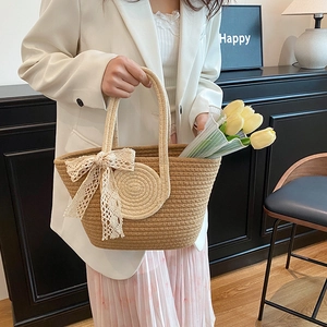Large woven tote bag with a white lace bow and contrasting handles for summer beach fashion