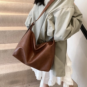 Vintage brown leather hobo bag with large capacity shown on model at a staircase