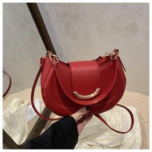 Gros plan sur le sac demi-lune en cuir rouge avec détail de fermoir en métal doré