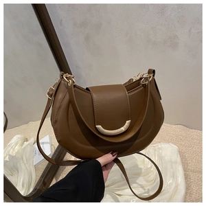 Détail d'un sac demi-lune en cuir marron avec boucle en métal doré et bandoulière réglable
