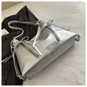 Detailed view of silver metallic tote bag with decorative bow and functional dual zippers