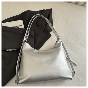 Close-up of metallic silver hobo bag with adjustable wide strap on black suit jacket