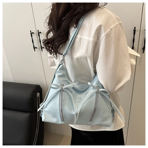 Model wearing a light blue bow tote bag with matte leather finish and double zippers