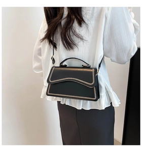 Détail du sac bandoulière noir avec coutures en V blanches et sangle réglable sur mannequin