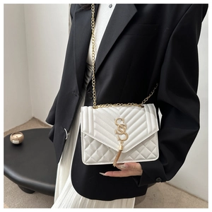 Detail of white quilted crossbody bag with gold chain strap and stylish tassel accent