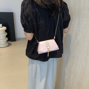 Sac bandoulière rose brillant avec chaîne dorée et logo sur fond de style minimaliste