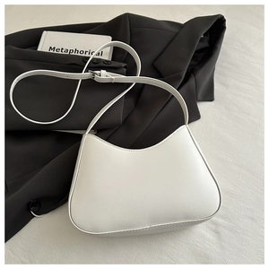 Detail view of the white crescent bag with smooth leather finish on a white fabric base