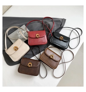 Flat lay macro of five retro faux leather crossbody bags with golden U-shaped buckles