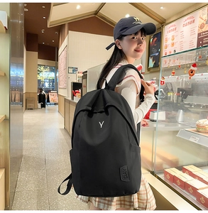 Detail of minimalist black nylon backpack featuring white embroidery and Y-shaped design