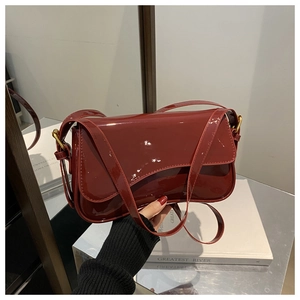 Detail showing high-gloss wine red patent leather surface and golden metal hardware