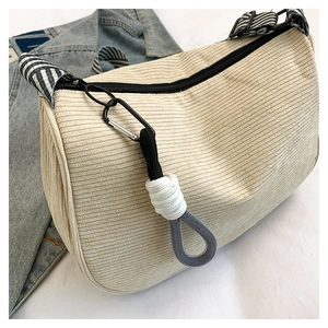 Detail showing off-white corduroy texture and striped shoulder strap of the bag
