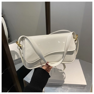 Detailed close-up of glossy white patent leather handbag with wavy flap and gold hardware
