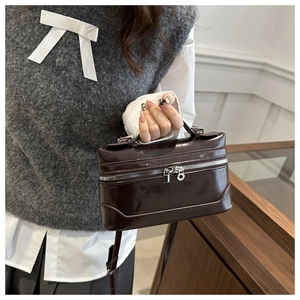 Detailed close-up of dark brown mini box bag with shiny finish and silver zippers