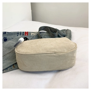 Detail of beige corduroy crossbody bag with black and white striped woven shoulder strap