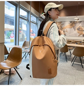 Detail of a large brown and beige nylon backpack with Y embroidery on a model