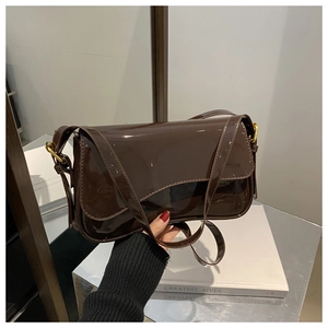 Detailed close-up of brown patent leather texture and gold buckle on retro handbag