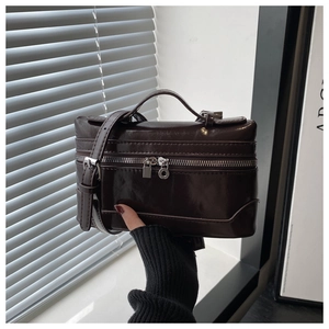 Detail of dark brown polished leather vanity bag showing dual zippers and silver hardware