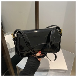 Detailed view of the asymmetrical glossy black patent leather flap and gold metal buckle