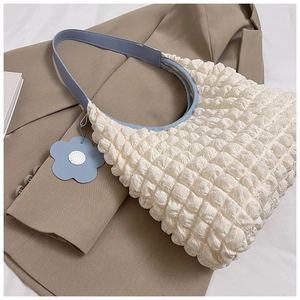 Vue détaillée du sac cabas blanc texturé gaufré avec bandoulière bleue et charme de fleur