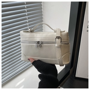 Detail of cream white box bag showing metal zipper and adjustable faux leather strap