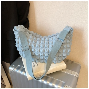 Detail of light blue cloud bag featuring 3D puff texture and adjustable canvas strap