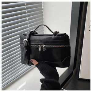 Detail of minimalist black handbag with silver lock and adjustable shoulder strap