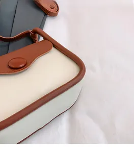 Close-up of contrast color crossbody bag with beige leather and brown trim details