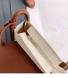 Close-up of golden zipper hardware and contrast leather on the beige shoulder bag