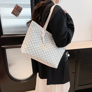 White leather tote bag with M-letter monogram print and gold pendant shown on model