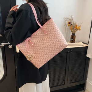 Pink tote bag with Monogram M print and gold metal pendant worn by a female model