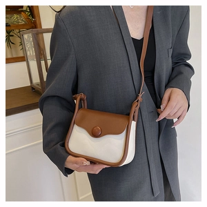 Detailed close-up of a retro contrast shoulder bag on a model wearing a blazer