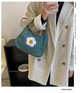 Close-up of dark green baguette bag with sunflower embroidery on white corduroy suit