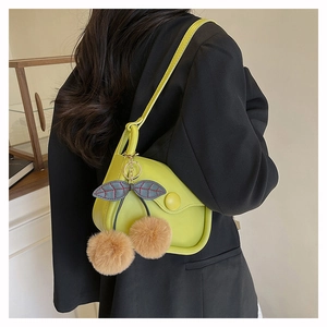 Close-up of light green saddle bag with cherry charm accessory on a black blazer