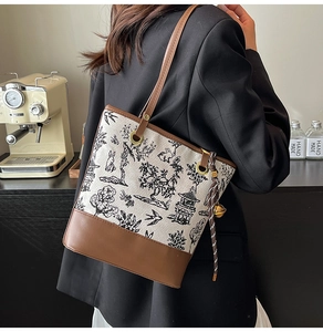 Vue détaillée du sac seau en toile blanche brodée avec des motifs de peinture à l'encre