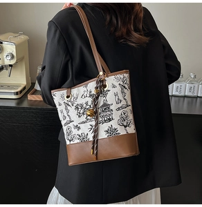 Gros plan d'un sac seau en toile avec broderie chinoise et finitions en cuir sur un mannequin