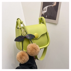 Detailed close-up of lime green crossbody bag featuring brown plush balls and leaf charm