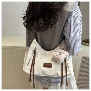 Dettaglio della borsa a spalla in tessuto bianco con etichetta in pelle e orsetto rosa