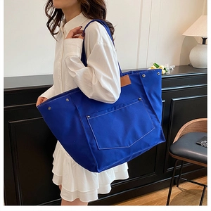 Détail du cabas en toile bleu Klein avec surpiqûres blanches et rivets métalliques
