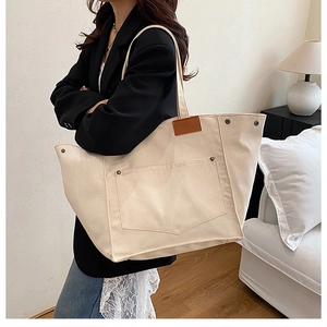 Vue détaillée d'un grand sac cabas en toile beige avec poche frontale et patch en cuir