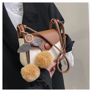 Detail view of contrast color shoulder bag with a unique plush cherry charm on flap