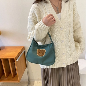 Green teddy bear baguette shoulder bag worn with vintage style knit cardigan