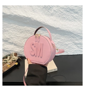 Detail of pink round handbag showing the textured leather and embossed SM logo