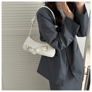 Détail du sac baguette blanc avec boucles dorées sur une surface élégante en similicuir