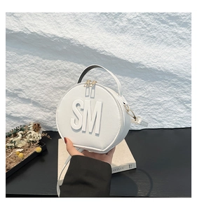 Detail of white round cross-body bag featuring 3D letters and golden metal hardware