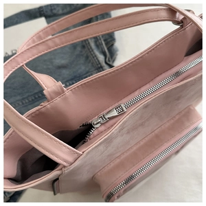 Detailed macro view of pink tote bag showing smooth silver zipper and soft suede texture