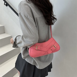 Sac sous le bras rose en similicuir avec boucles métalliques sur des escaliers gris
