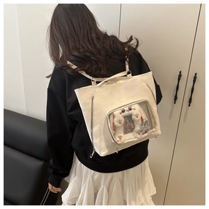 Detail view of a white Ita bag featuring a large transparent window for plush doll display