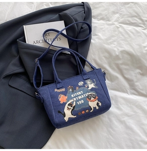 Detail of cartoon denim tote bag with cat patterns on a stylish blazer background