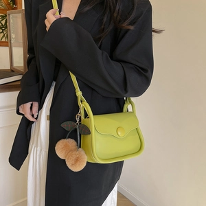 Chic avocado green saddle bag with cherry charm and black shoulder strap for women